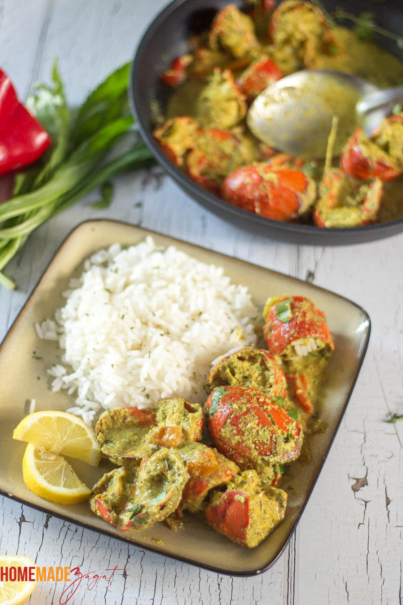 A plate of lobster curry with white rice and lemons.