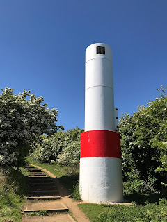 Hawkcraig Point Range Rear Light - an automated lighthouse painted white and red with stairs running up the grassy hill at the side of it.  Photo by Kevin Nosferatu for The Skulferatu Project.