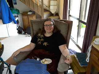 Heather sitting in comfy chair with pork bun and embroidery on her lap.