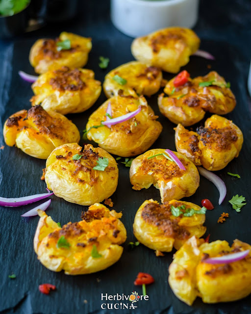 Air Fried Masala Smashed Potatoes topped with red onions.