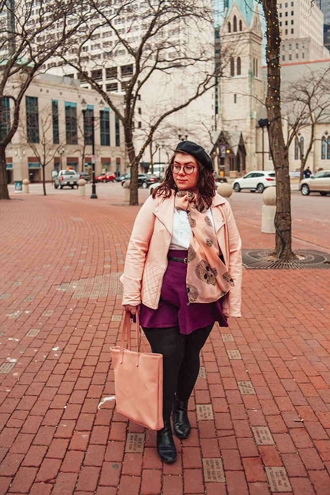 An outfit of a black beret, pink peplum faux leather jacket, vintage white pleated blouse, pink geometric skull print scarf tied in a bow, purple skater skirt, black tights and black boots.
