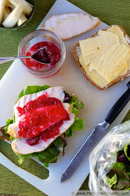 image of a making a turkey sandwich with cranberry salsa, cheese, kohlrabi pickles, lettuce, and bread