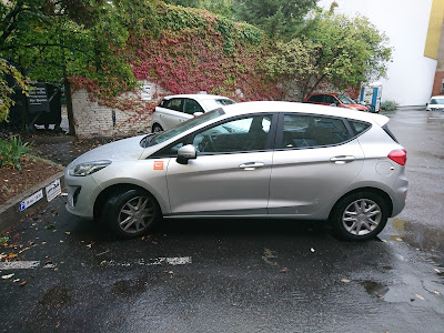 Silberner Ford Fiesta von Cambio-Carsharing geparkt auf einem Berliner Hof. Im Hintergrund eine alte Mauer.