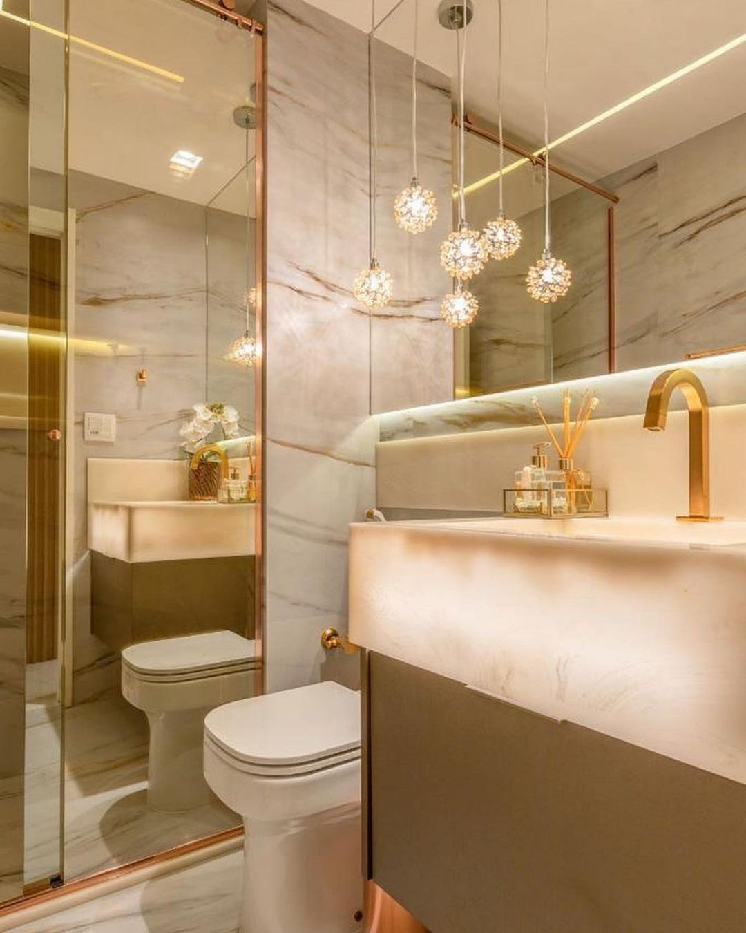 Banheiro com box espelhado até o teto e bancada de ônix iluminada