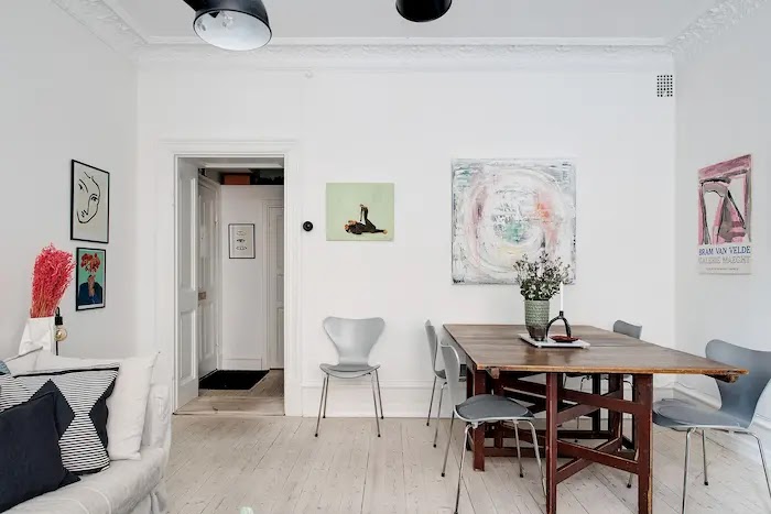 Trucos para aprovechar mejor el espacio en casas pequeñas Mesa de comedor con gran capacidad adosada a la pared en un salón pequeño