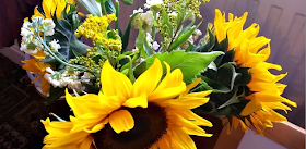 A vase with sunflowers and other random flowers in