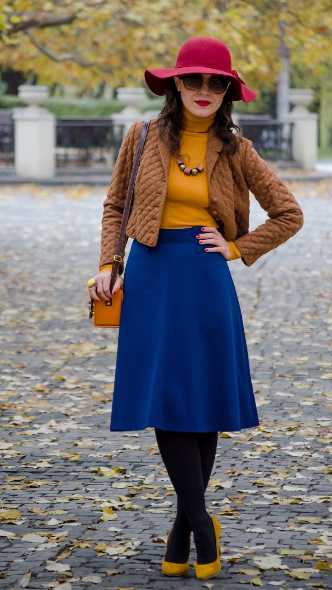 blue skirt mustard turtleneck sweater burgundy floppy hat brown jacket box satchel mustard heels autumn fall scenery leaves