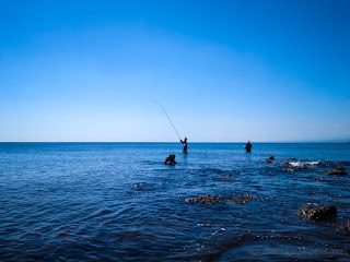 Tropical Rocky Fishing Beach Panorama With Two Fishermen Fishing On A Sunny Day At The Village Umeanyar North Bali Indonesia