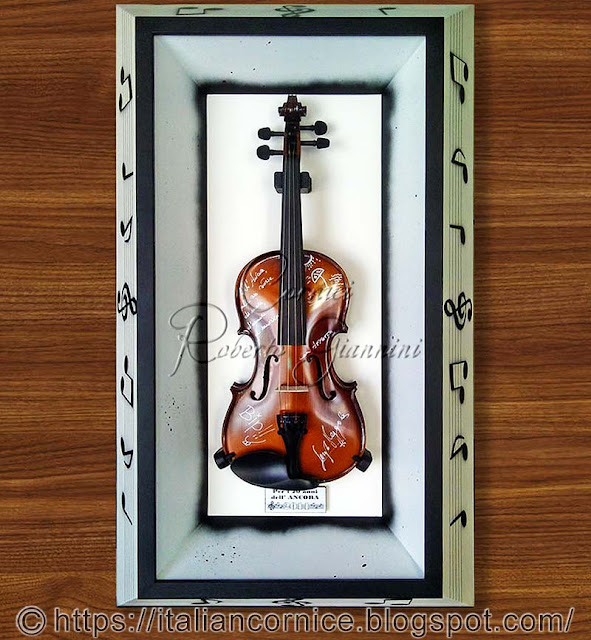 Violino chiuso in una cornice teca decorata con note musicali
