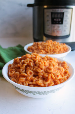 Make homemade Spaghettios in your instant pot. This easy meal will make you relive your childhood in the tastiest kind of way! looking across two bowl of homemade coypcat spaghettios in tomato sauce with instant pot in background