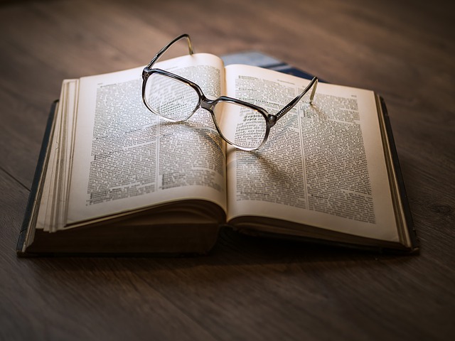 Foto ilustração do texto sobre venda de imóvel locado onde se vê um óculo redondo sobre um livro que esta aberto em cima de uma mesa de madeira nobre.