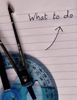 Compus on top of a blue protractor on lined paper with an arrow pointing to the words what to do 