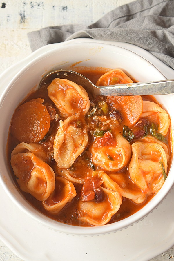 birdseyeview of a white bowl having minetsrone soup with tortellini