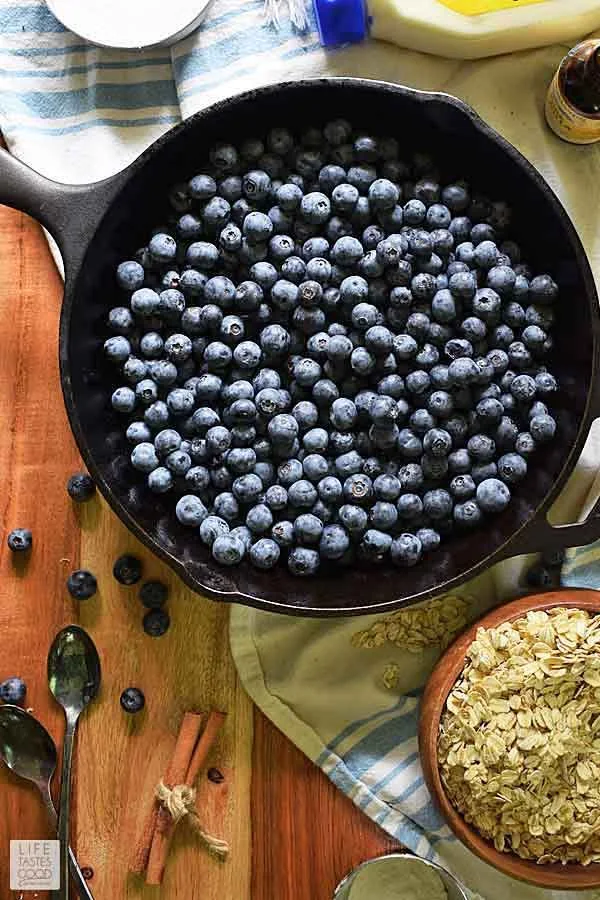 Overhead view of cast iron skillet with 4 cups of blueberries for blueberry crisp recipe