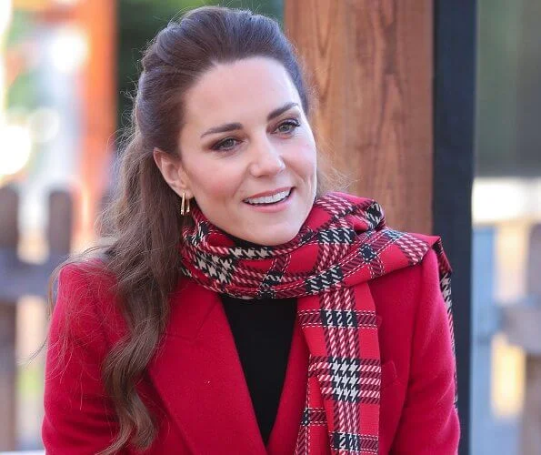 Kate Middleton wore a tartan pleated skirt from Emilia Wickstead, yellow gold hoops from Spells of Love. Alexander McQueen red coat. Grace Han bag