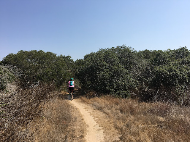 Amber biking away on a dirt trail