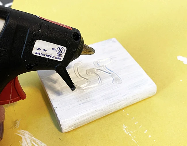 glue gun with glue on white wood scrap