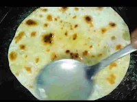 Applying ghee on kulcha cooking on a pan or tawa