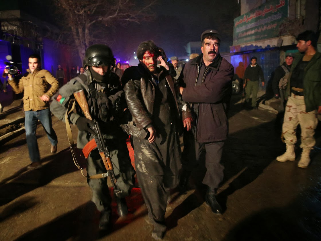   Afghanistan security forces help an injured man from the scene of the attack, where at least 21 — mostly foreigners — were killed.