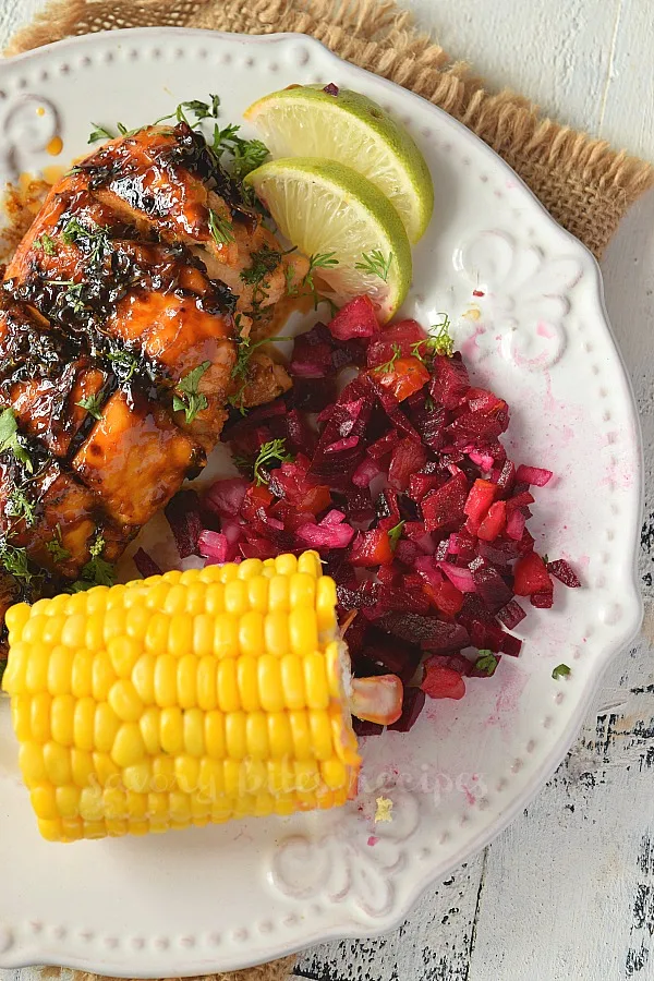 delicious griiled honey lime cilantro chicken served on a plate with corn on the cob and beet salsa