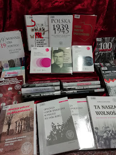 Wystawka książek na tle czerwonej tkaniny. Wśród nich między innymi "Opozycja i opór społeczny w Polsce po 1956 roku", "Drugi obieg w PRL" i "Najwyższa Izba Kontroli. Sto lat troski o państwo".