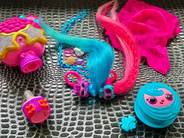 Showing the contents of the pop pop hair surprise including twin pets in purple with long blue hair and blue with long pink hair