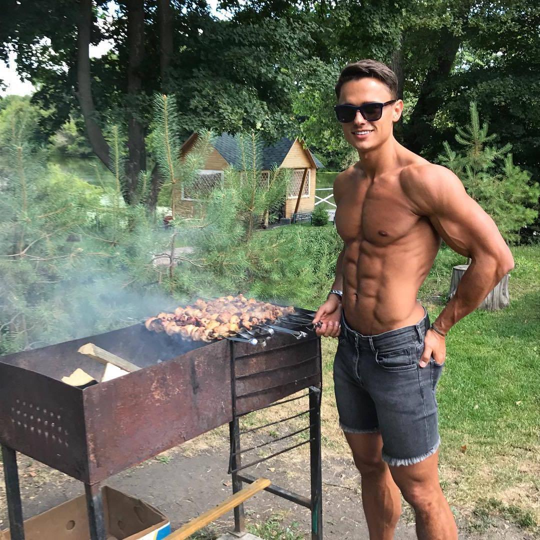 cute-shirtless-male-model-slim-fit-body-abs-gay-twink-smiling-sunglasses-grilling-meat-backyard