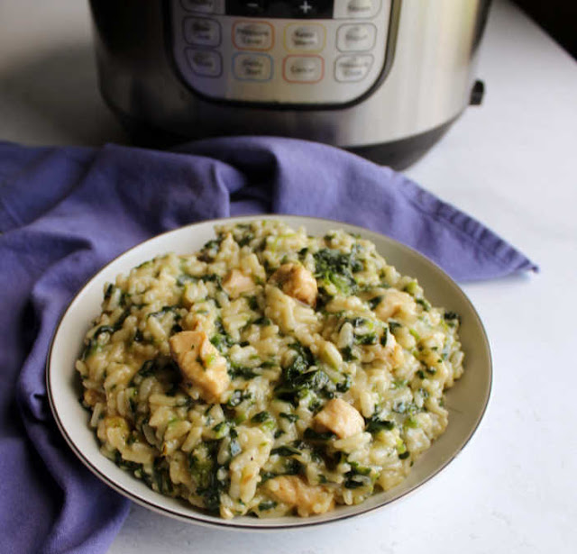 close bowl of risotto with small bits of spinach and chunks of chicken