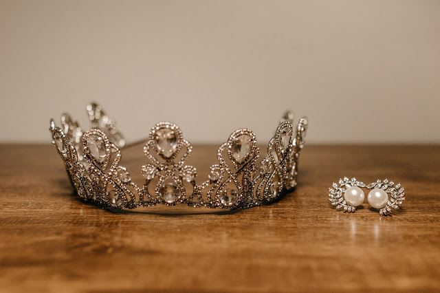 A tiara and a pair of earrings on top of a wooden surface.