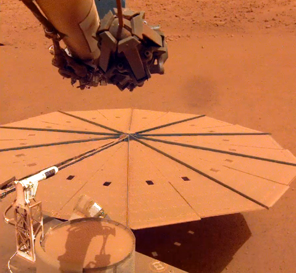 One of InSight's two large solar panels is completely covered in Martian dust...as seen by a camera on the lander's robotic arm. One of InSight's two large solar panels is completely covered in Martian dust...as seen by a camera on the lander's robotic arm.
