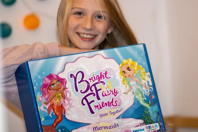 A young girl holding a box which says "Bright Fairy Friends shine together"