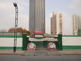 two Chinese funeral wreaths and banner with "黑心公司：还我农民工血汗钱" on an entrance to a construction site in Shanghai