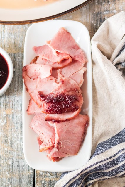 Sliced ham on a white serving platter.
