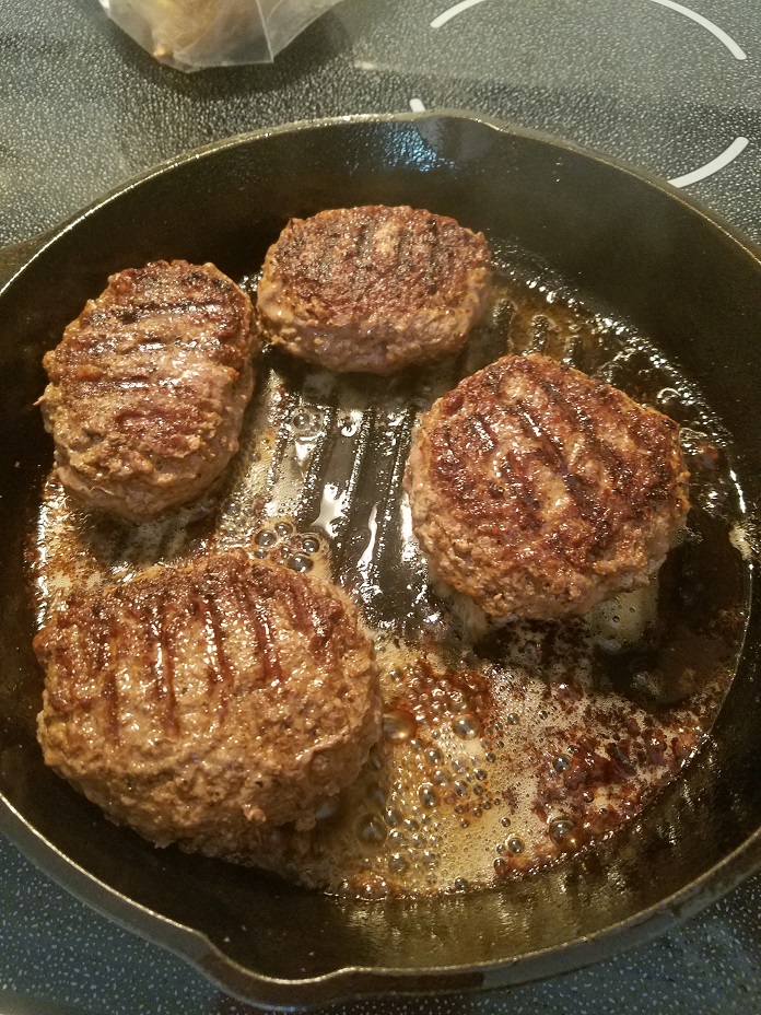 these are salisbury steaks frying in an iron skillet