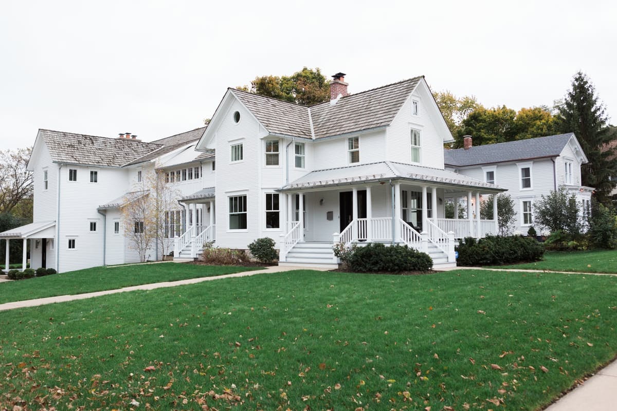 Magnificent white traditional farmhouse in Illinois with front porch and steel roofing on Hello Lovely Studio