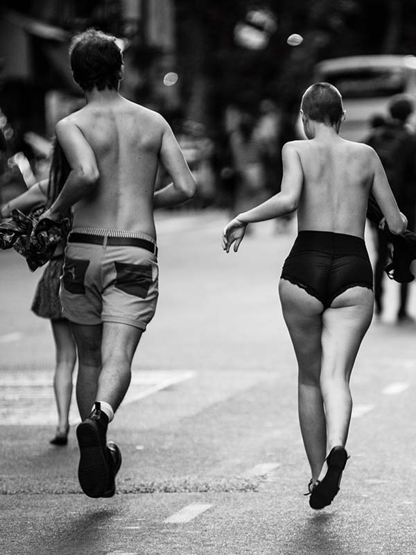 dos personas corren con el torso desnudo por el asfalto de la ciudad