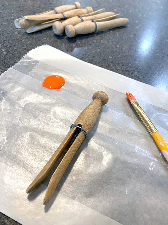 painting clothespin carrots, orange paint and brush