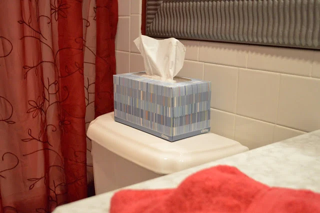 Red shower curtain in red bathroom with a blue tissue box on the toilet back