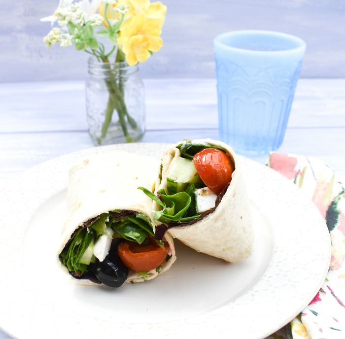 Vegan Greek Salad Wrap on a teaplate next to a glass of water