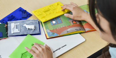 a person feeling 3d printed books with their hands