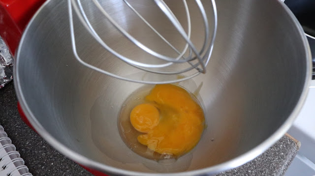 whisking one egg and an egg yolk in the bowl of a kitchen aid