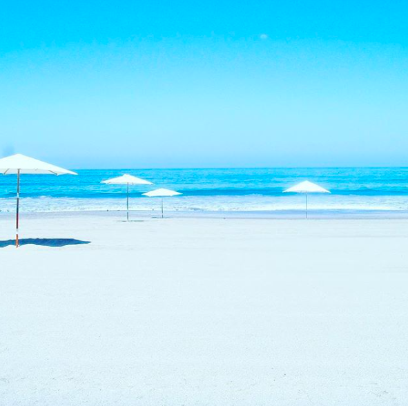 white sand beach with white sun umbrellas and blue sea iquique chile