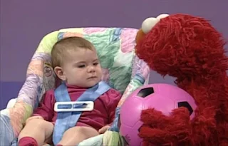 Elmo goes to a baby and puts the ball in the baby's lap. The ball drops to the ground and they watch it bounce. Elmo's World Balls Kids and Baby