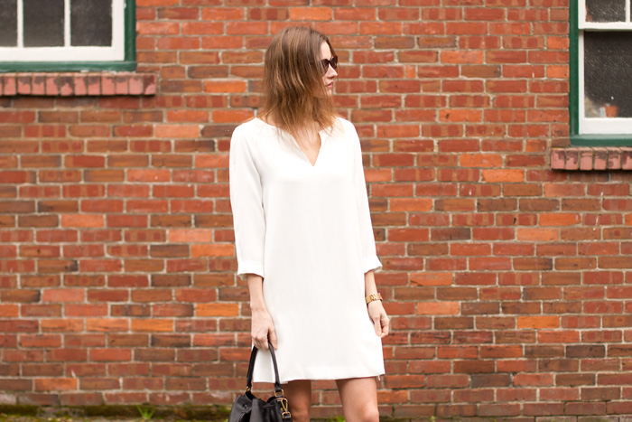 Vancouver fashion blogger, Alison Hutchinson, is wearing a white Zara dress, black Vince boots, a black leather Madewell bucket bag, and YSL sunglasses from Smart Buy Glasses