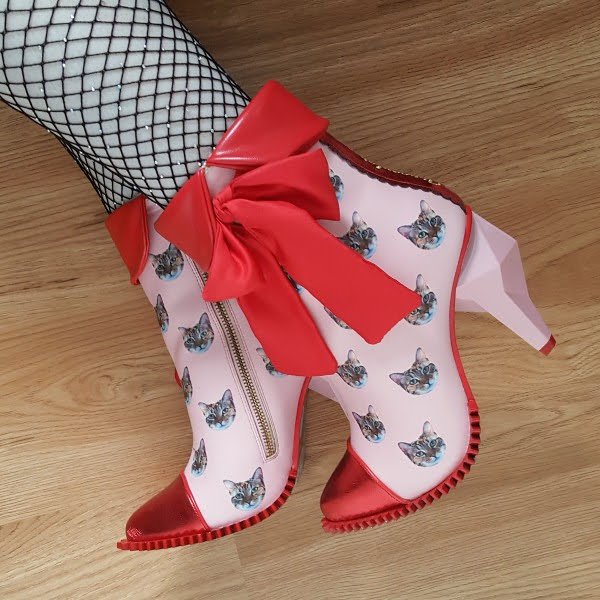 feet wearing cat print ankle boots with red details and bow