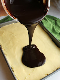 pouring dark chocolate ganache over creamy layer of german buttercream