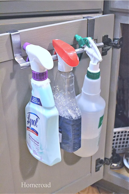 spray bottles hanging from cabinet door towel rack