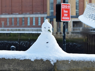 A snowman and a Covid warning sign near the Millennium Bridge