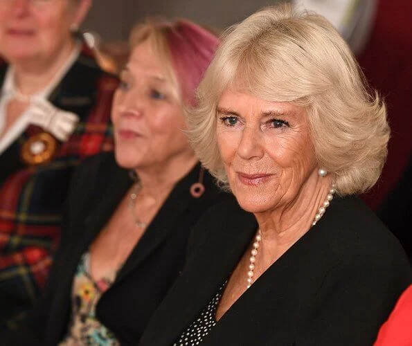 The Duchess of Cornwall sports a chic polka dot dress and ultra stylish cape at a reception for National Literacy Trust