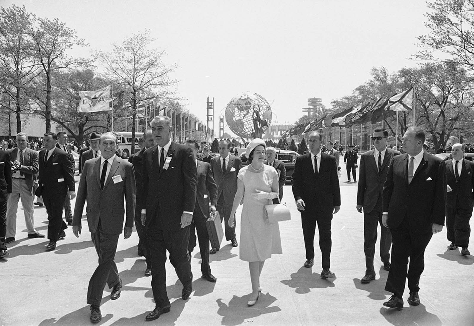 President Lyndon B. Johnson is flanked by Lady Bird Johnson and Norman K. Winston, head of the U.S. Pavilion as he walks through the New York World's Fair grounds on his way to the U.S. Pavilion on May 9, 1964.